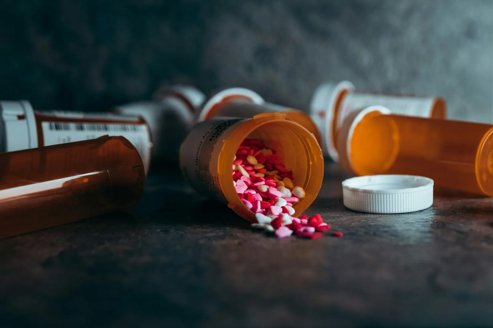 Frascos de medicación volcados con pastillas sobre la mesa