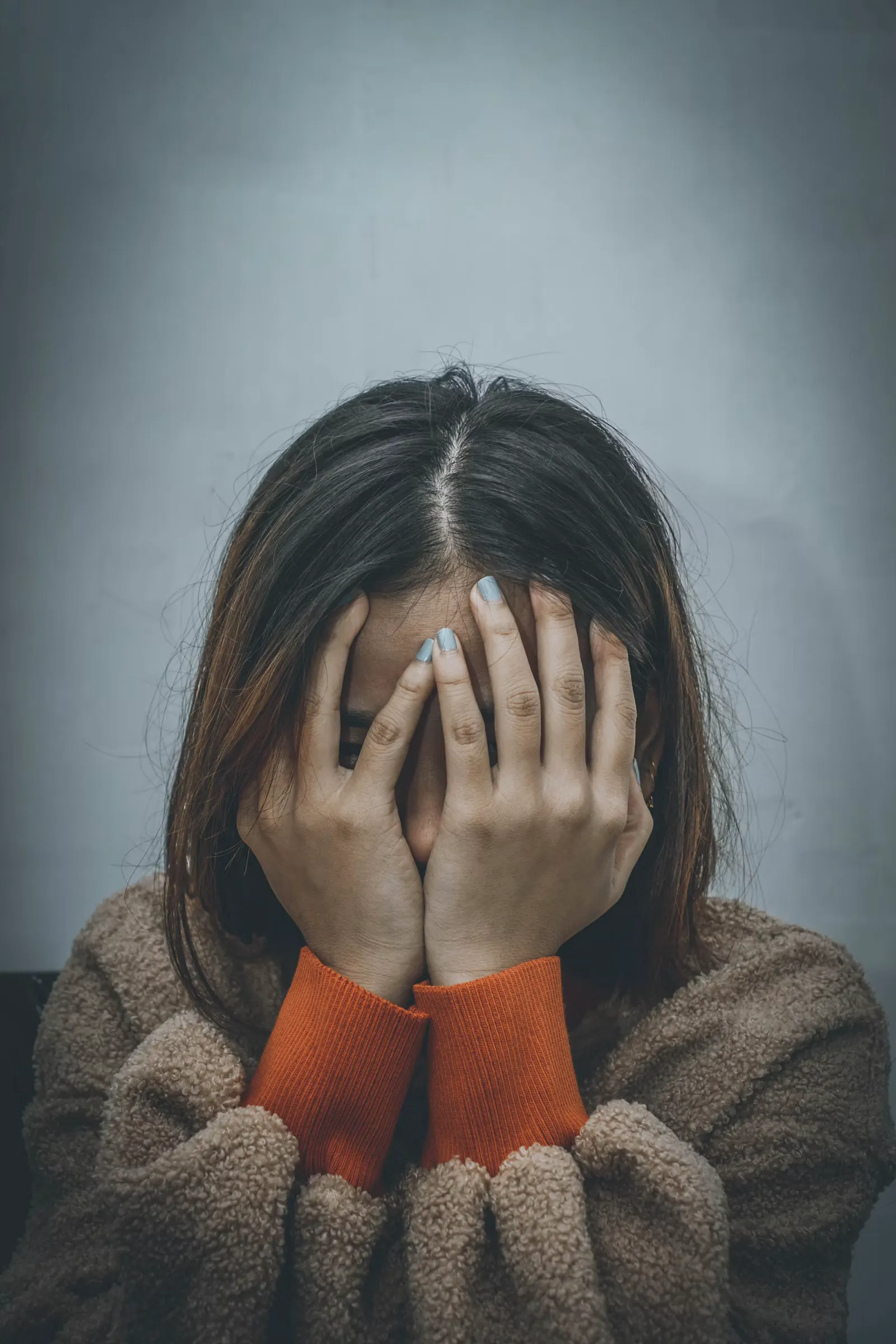 Mujer cubriéndose el rostro con la mano
