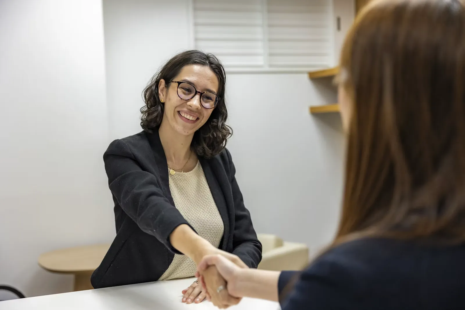 Dos mujeres se dan la mano en una entrevista de trabajo