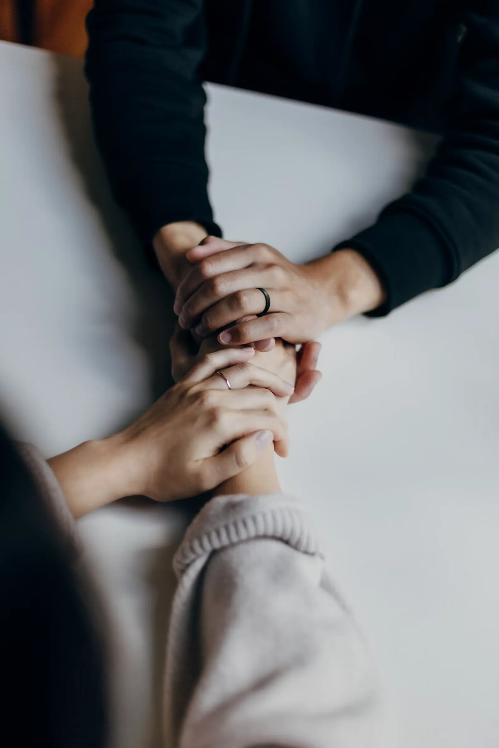 Dos personas tomadas de la mano sobre la mesa, en un gesto de acompañamiento