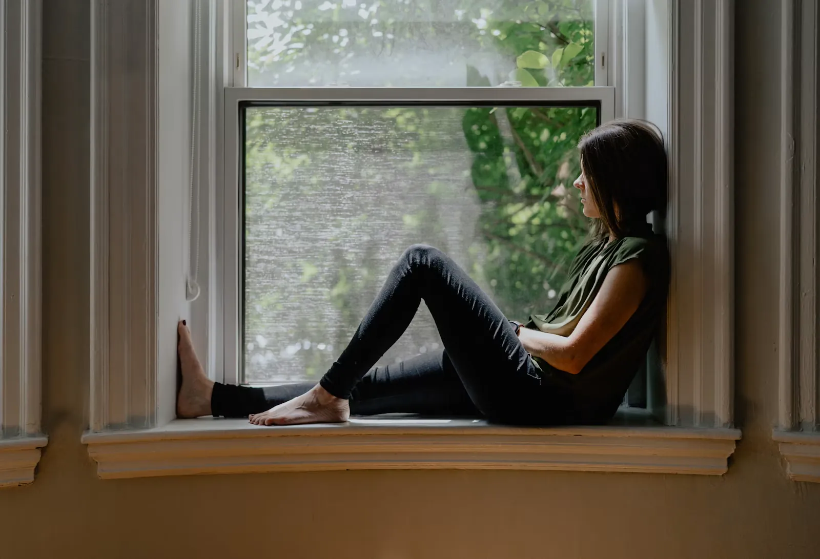 Mujer sentada en el alféizar de una ventana