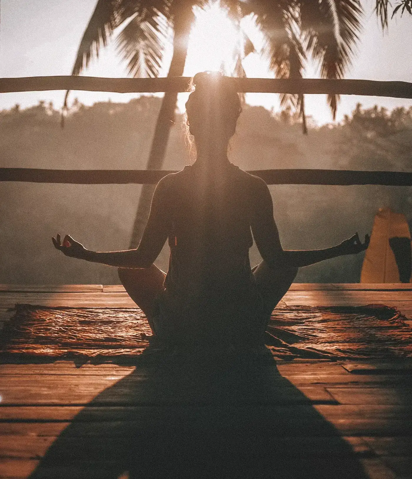 Mujer meditando sobre el piso de madera a la luz de la mañana