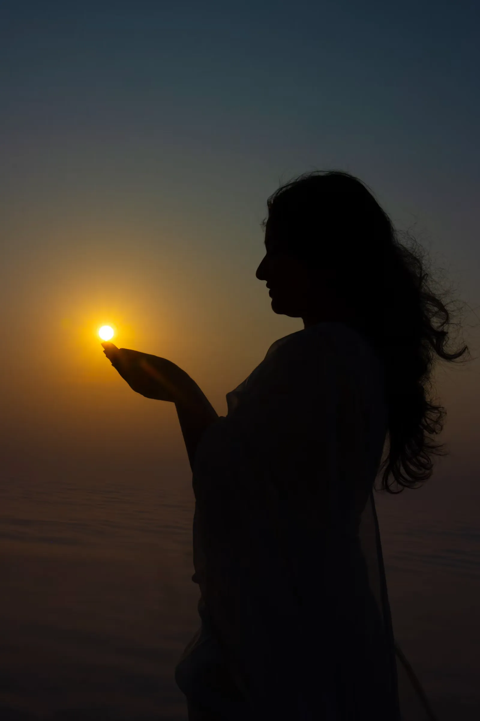 Silueta de una mujer que sostiene la luz del sol entre sus manos