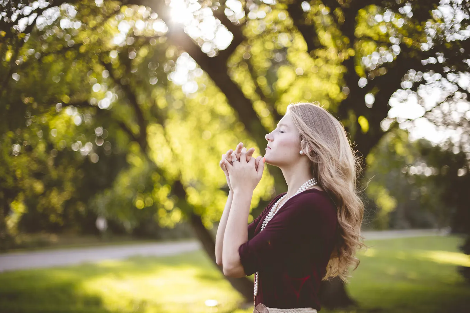 Mujer en oración bajo un árbol