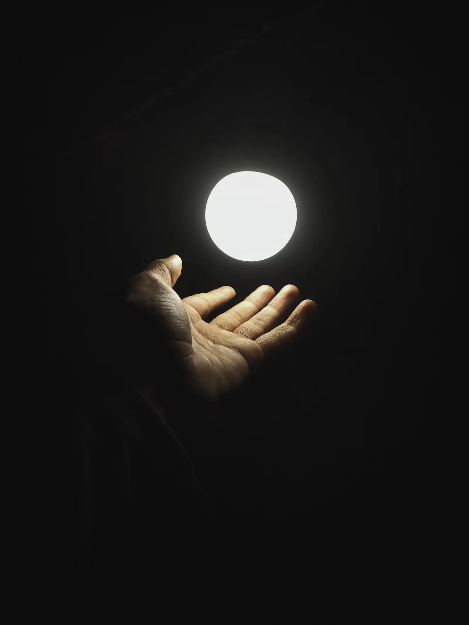 Una mano sosteniendo una luz en la oscuridad